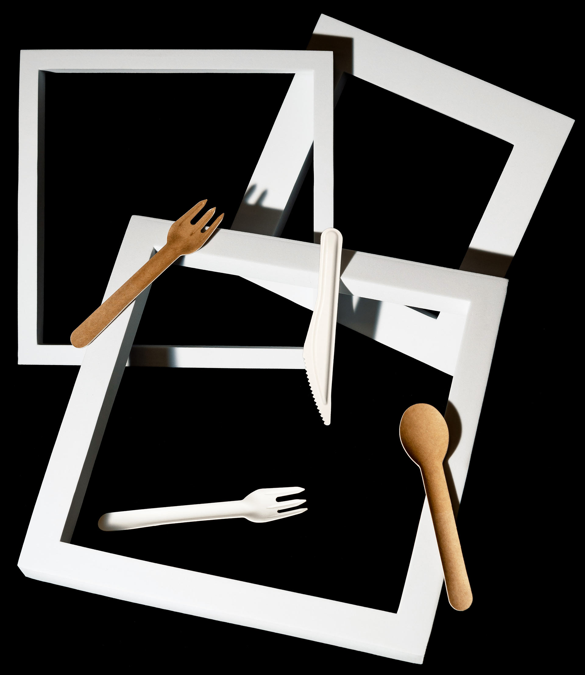 Paper forks and spoons on a black background with white squares