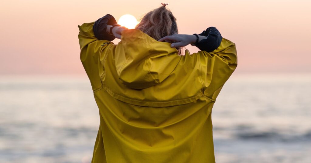 Girl wearing a yellow raincoat at sunset