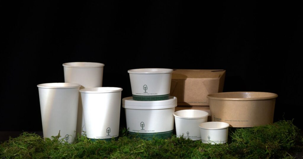 single-use paper containers and cups on green moss with black background